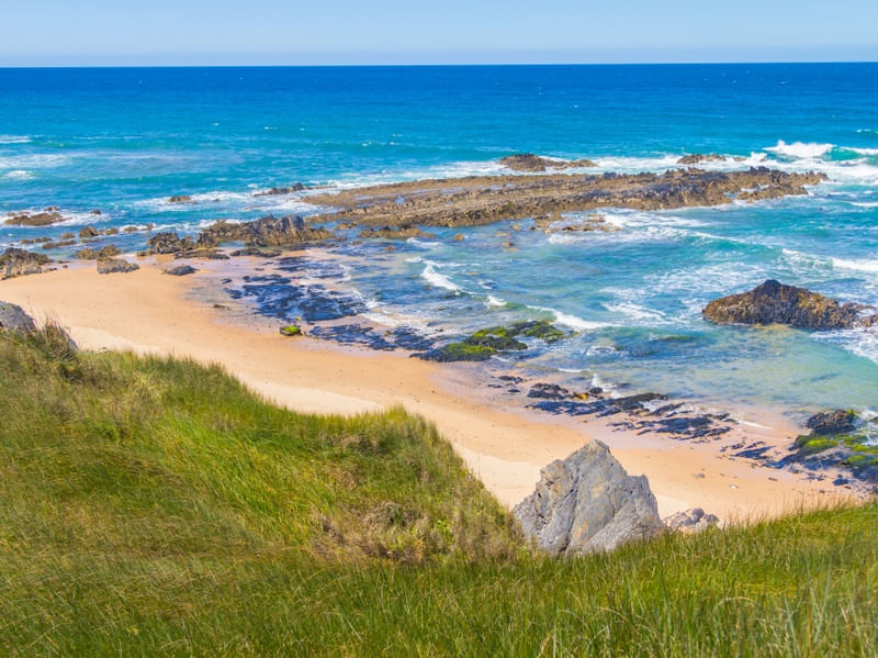 PRAIA COM ROCHAS, AREIA E VEGETAÇÃO