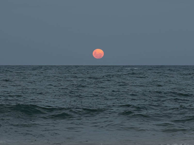 FULL MOON RISES ABOVE OCEAN