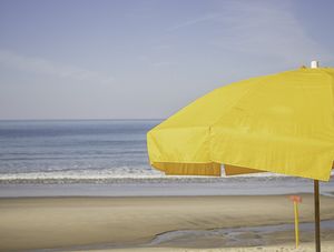 GUARDA SOL AMARELO COM MAR AO FUNDO