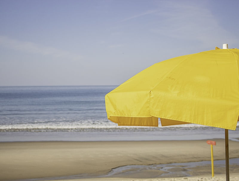 GUARDA SOL AMARELO COM MAR AO FUNDO