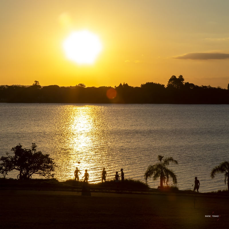 JOGANDO BOLA COM SILHUETA EM FRENTE AO LAGO