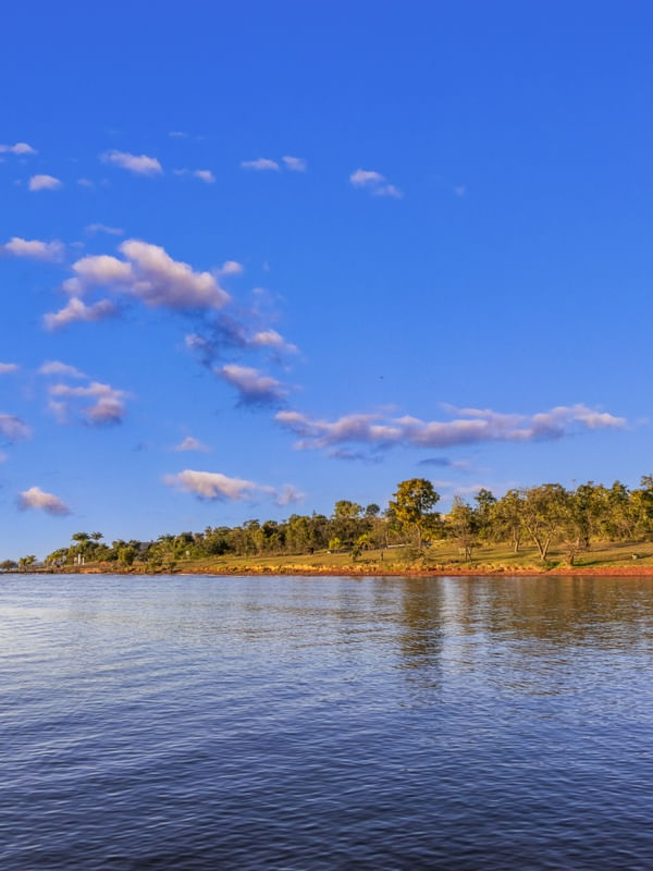LAGO DE ÁGUAS CALMAS COM CÉU AZUL.
