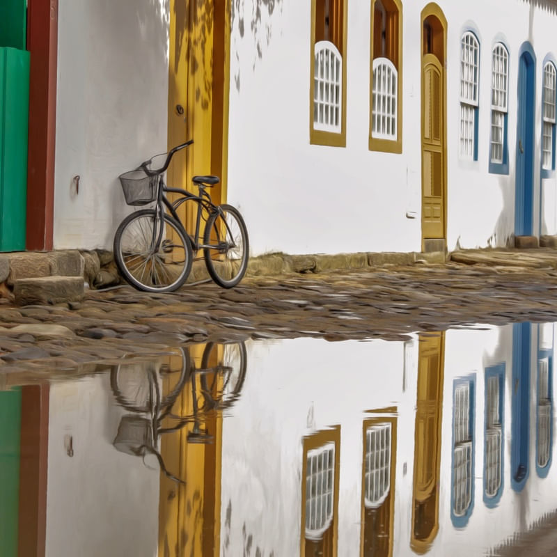 FOTO DE PAISAGEM DE CASARÕES EM PARATY COM BICICLETA. EDIÇÃO DIGITAL.