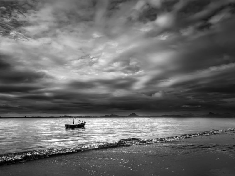 BARQUINHO SOB O CÉU NUBLADO NO MAR