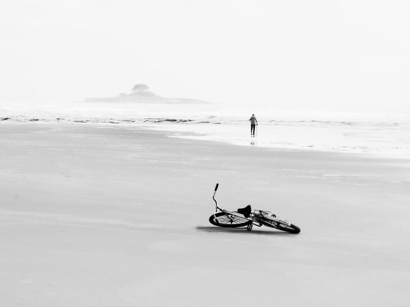 HOMEM SOLITARIO COM SUA BICICLETA NA PRAIA
