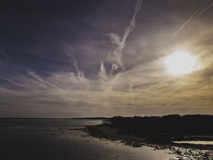 BELO PÔR DO SOL NA PRAIA COM UM CÉU AZUL COM REFLEXOS LARANJA
