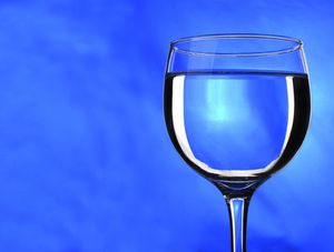 TAÇA DE CRISTAL COM ALIANÇA CAINDO DENTRO NO FUNDO AZUL
