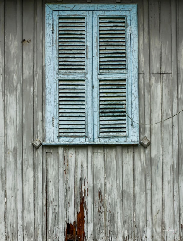 JANELA AZUL EM PAREDE DE MADEIRA DESGASTADA