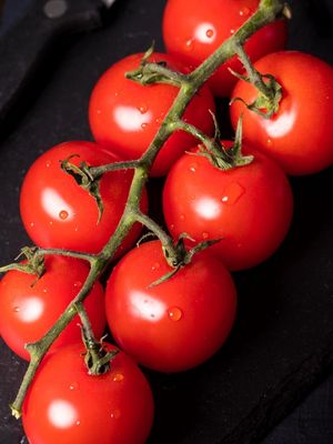 TOMATE CEREJA COM GOTÍCULAS DE ÁGUA SOBRE A MESA