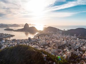 NASCER DO SOL ATRÁS DO PÃO DE AÇÚCAR E O BAIRRO DE BOTAFOGO NO RIO DE JANEIRO COM CÉU AZUL