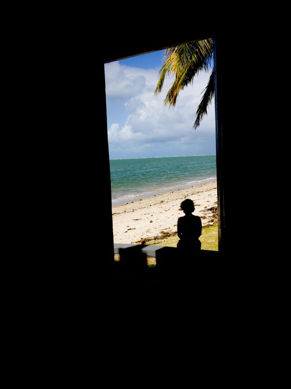 MULHER NA JANELA OBSERVANDO A PRAIA EM PRAIA DOS CARNEIROS